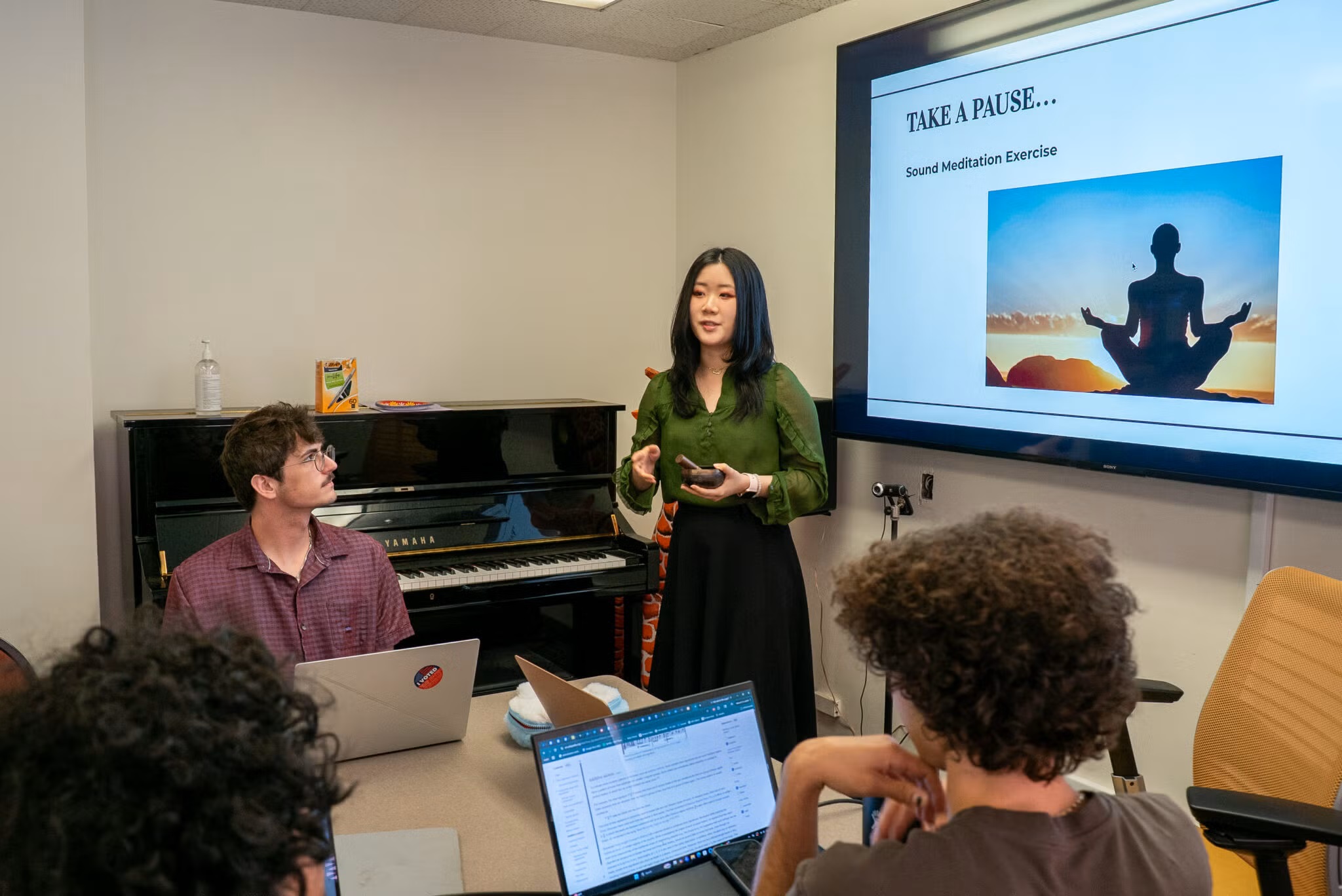 Students gathered at table for Musicology Senior Capstone presentation.